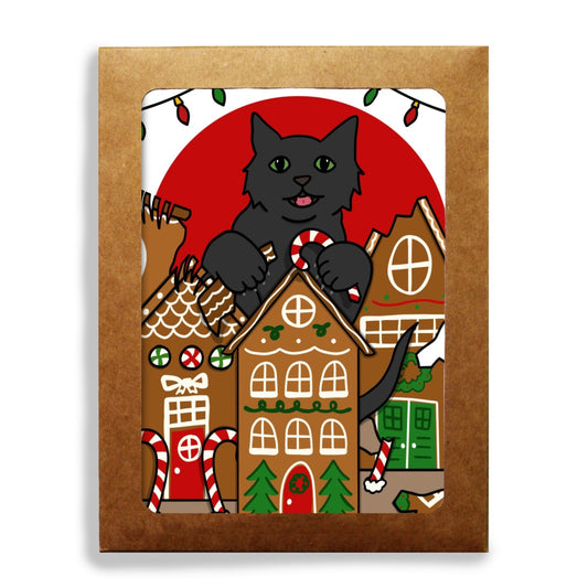 A stationery set featuring a whimsical holiday illustration of a black cat with green eyes destroying gingerbread houses, holding candy canes, with a large red sun and Christmas lights in the background.