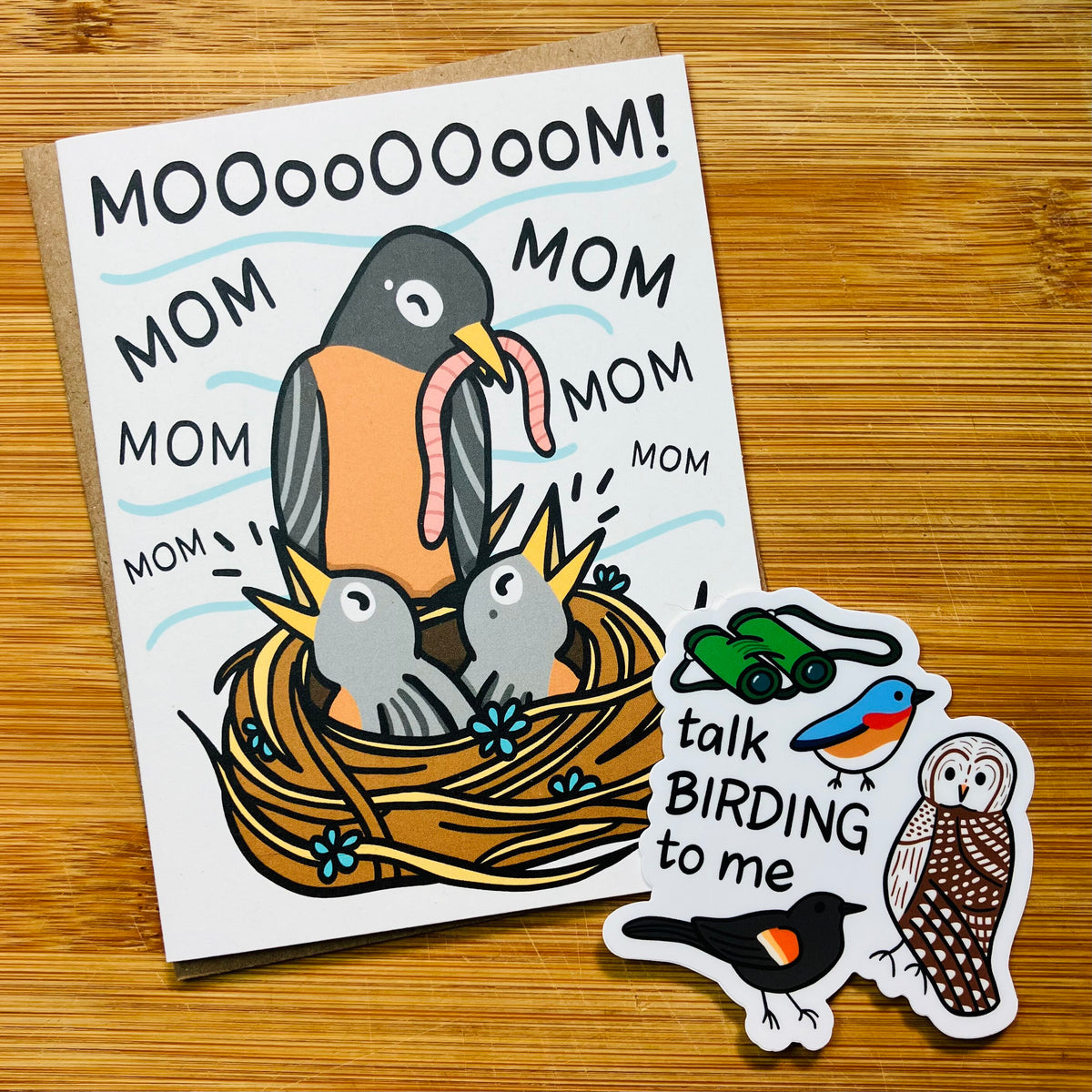 A bird-themed Mother's Day card and a 'talk birding to me' sticker photographed against a wood background.