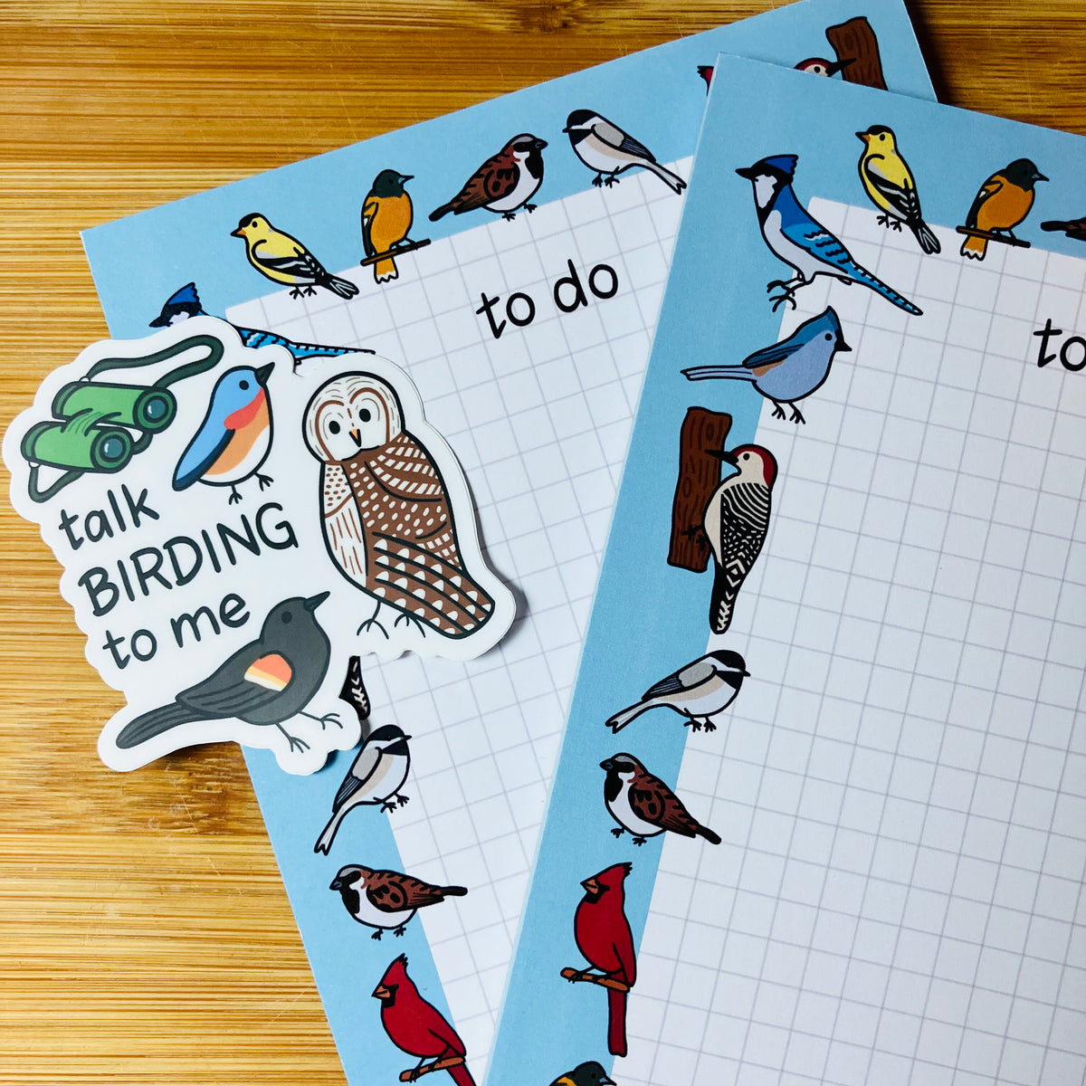 Bird-themed to-do lists with colorful bird illustrations around the border, plus a die-cut sticker that says "talk BIRDING to me", shown on a wooden surface.